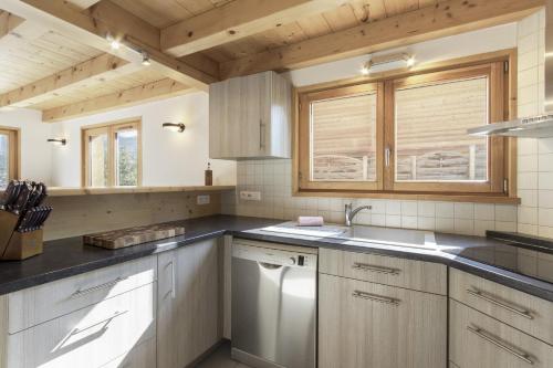 eine Küche mit weißen Schränken und einer Spüle in der Unterkunft Chalet Saint-Pierre jacuzzi vue montagne neuf in Le Fayet