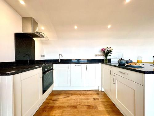 a kitchen with white cabinets and black counter tops at 1 Bed in Bude 88499 in Morwenstow