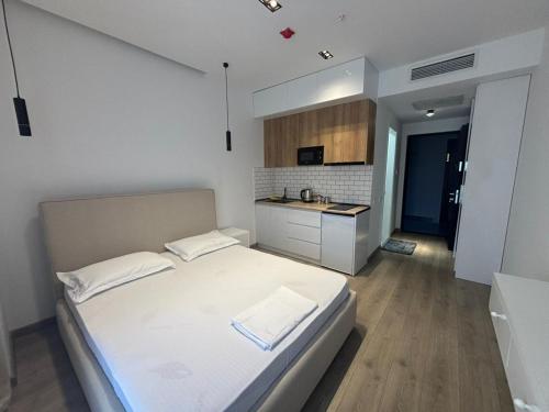 a bedroom with a large white bed and a kitchen at Thom Tower in Gonio