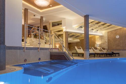 a pool in a hotel with chairs and tables at Hotel Jäger 3Sterne Superior in Tux