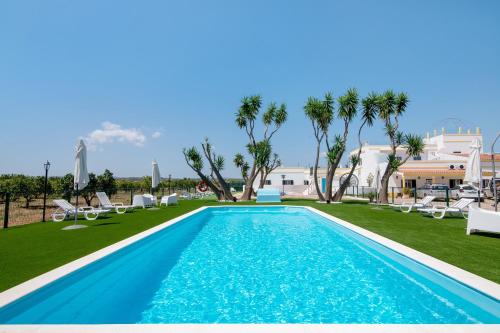 a pool with chaise lounge chairs and palm trees at Quinta Alegre Tavira T3 in Luz de Tavira