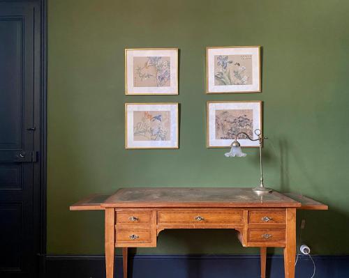 a wooden desk against a green wall with pictures at Le Gîte de Little Castle campagne à 1 h de Paris in Trie-Château