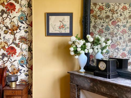 a room with flowers in a vase on a fireplace at Le Gîte de Little Castle campagne à 1 h de Paris in Trie-Château