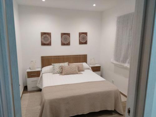a white bedroom with a bed and two night stands at Casa Sabela in Tomiño