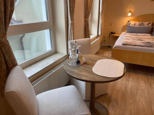 a room with a table and a bed and a window at Hotel Deichvoigt in Cuxhaven