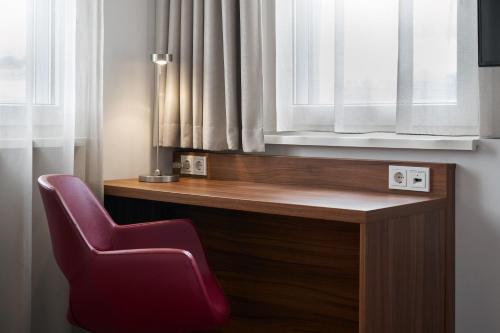 a red chair sitting in front of a window at Four Points Flex by Sheraton Essen in Essen