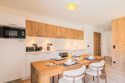 a kitchen with a wooden table and white cabinets at TERRESENS - Les Sources de Canopée in Saint-Gervais-les-Bains