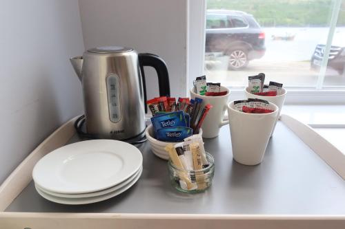 a counter with plates and cups and a coffee maker at Pink House Skye in Portree