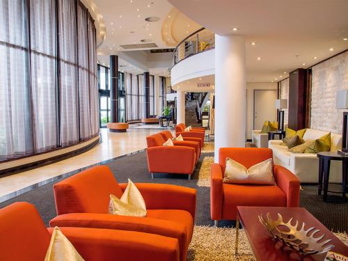 a lobby with orange chairs and couches at Premier Hotel East London ICC in East London