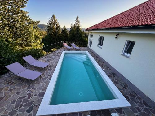 a swimming pool with two chairs and a house at Villa Pika in Delnice