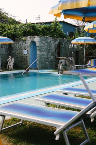 a swimming pool with chairs and umbrellas at Hotel Villa Cimmentorosso in Ischia