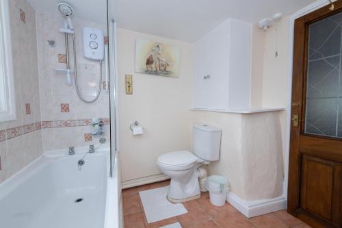 a white bathroom with a toilet and a shower at Magnolia Cottage in Wellington