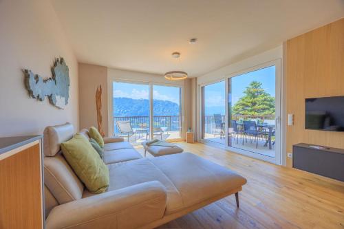 a living room with a couch and a large window at Adlerblick Penthouse mit Seeblick in Annenheim