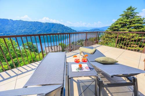 a table and chairs on a balcony with a view of the mountains at Adlerblick Penthouse mit Seeblick in Annenheim