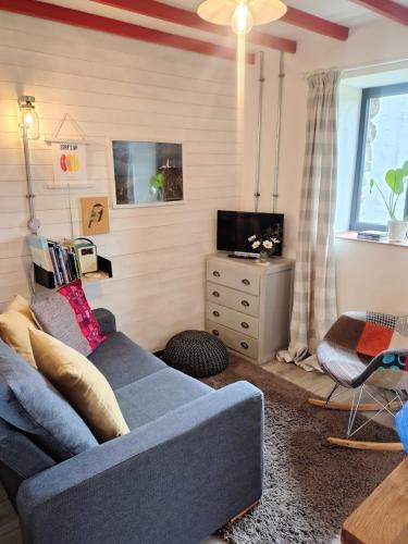 a living room with a blue couch and a tv at Grain Store Cottage in Narberth