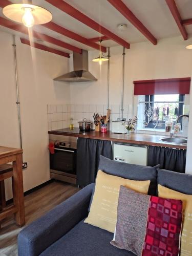a living room with a couch and a kitchen at Grain Store Cottage in Narberth