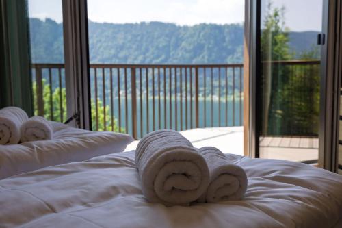 a bed with a towel on it with a balcony at Adlerblick Deluxe Annenheim in Annenheim