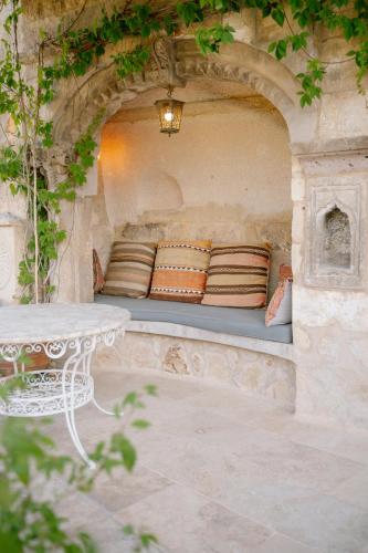 a bench in a stone wall with a table and pillows at Potamia Cave Suites in Ortahisar