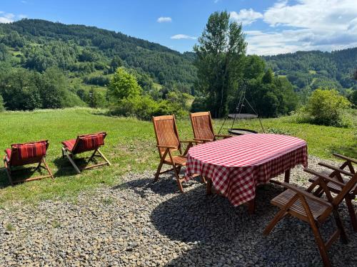 a picnic table and chairs with a view of a field at Chata na Wzgórzu in Ochotnica Dolna