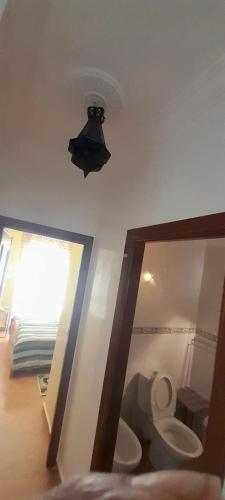 a bathroom with a toilet and a light on the ceiling at TANGER/ASILAH: APPART 50m2 FACE MER ET PISCINES, 5 PLACES, TOUT ÉQUIPÉ+WIFI+CLIM in Briech