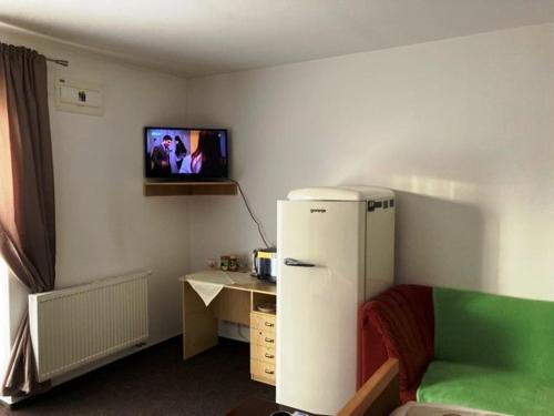 a room with a refrigerator and a tv on the wall at Izba s výhľadom na Tatry in Poprad