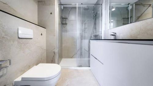 a white bathroom with a toilet and a shower at Baltic Infinity Beach Spa in Międzyzdroje