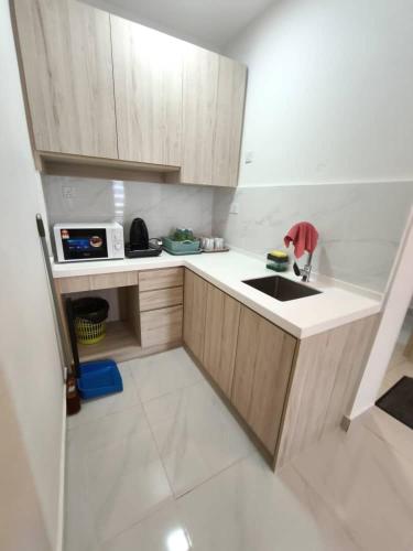 a small kitchen with a sink and wooden cabinets at BORNEO SUTERA BAY Homestay Services in Kota Kinabalu