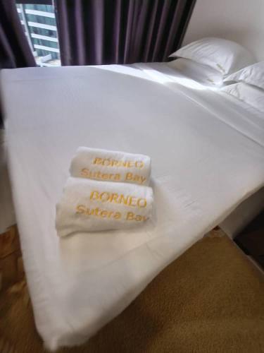 a bed with white sheets and pillows with the words remote summer daycano summer at BORNEO SUTERA BAY Homestay Services in Kota Kinabalu