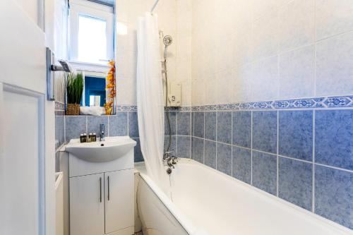a bathroom with a white tub and a sink and a bath tubermottermott at Ultra Luxury London w Kensington balcony condo in London