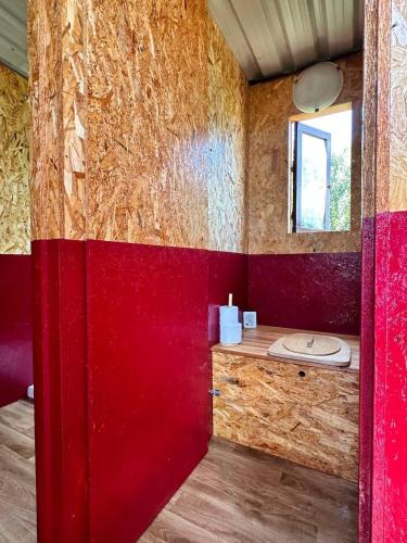 a bathroom with a red wall and a sink at Pauls caravan for 4 - See the horses from your bed in Barão de São João