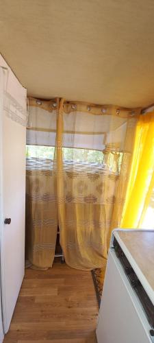 a room with a yellow curtain in a house at Pauls caravan for 4 - See the horses from your bed in Barão de São João