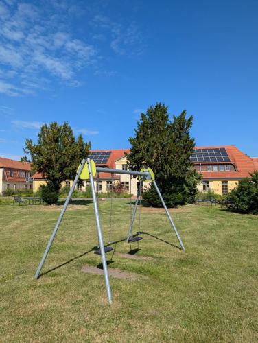 a swing set in a field with buildings in the background at Ferienwohnungen - barrierefrei - im sanierten Gutshof in Lalendorf