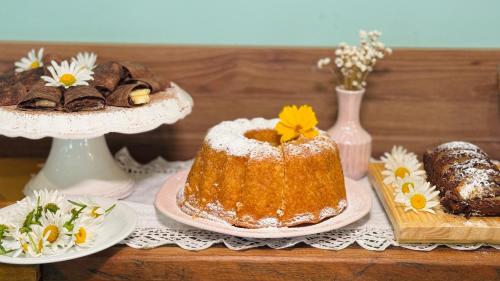 a table with a cake and some cookies and flowers at Pousada das Videiras boutique in Monte Verde