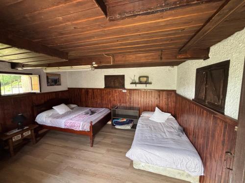 two beds in a room with wooden walls at Escondite en Peon in Villaviciosa
