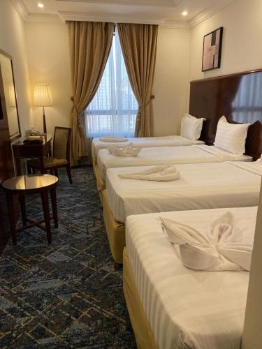 a hotel room with four beds and a table and a desk at فندق بارك رويال in Al Masfalah