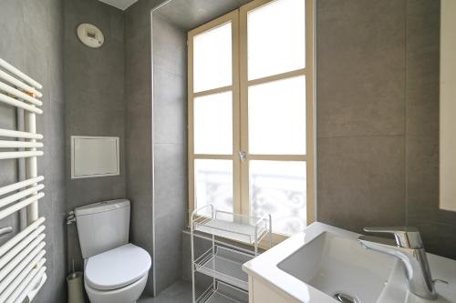 une salle de bain avec toilettes, lavabo et fenêtre dans l'établissement Lovely parisien apartment (opera 3), à Paris