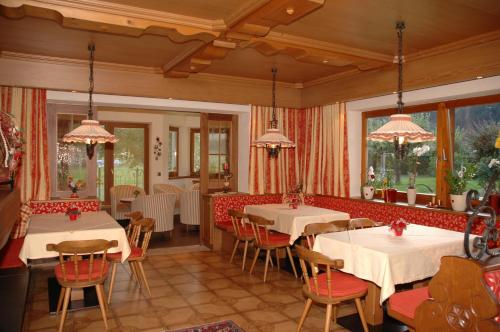 un restaurante con mesas y sillas blancas y ventanas en Hotel-Garni Almhof, en Mayrhofen