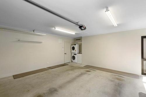 an empty white room with a kitchen and a microwave at Central Lower Hutt Gem - Steps to Queensgate & Station in Lower Hutt