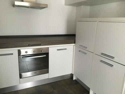 a kitchen with white cabinets and a stove at En Aparté in Porto-Vecchio