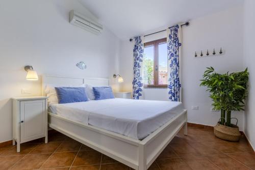 Un dormitorio con una gran cama blanca y una ventana. en Indaco Blu, en SantʼAnna Arresi