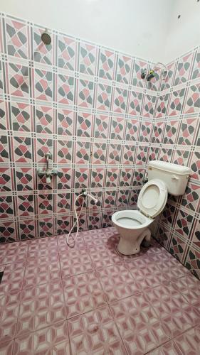 Un baño con inodoro y una pared de azulejos. en Vue Marine- 1bhk near Rock beach, en Pondicherry