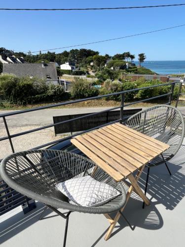 Ein Holztisch und ein Stuhl auf einem Balkon mit Meerblick in der Unterkunft STUDIO Vue Mer plage immédiate in Saint-Gildas-de-Rhuys