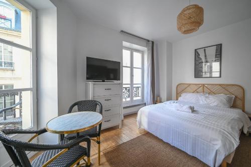 une chambre avec un lit, une table et une télévision dans l'établissement Opéra 2, à Paris