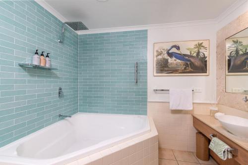 a bathroom with a tub and a toilet and a sink at Chic Couples Retreat in Port Douglas