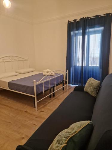 a bedroom with a bed and a couch and a window at Maiolica in Trapani