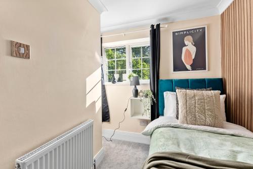 a bedroom with a bed with a blue headboard at Stylish 4 bed in Bracknell with Games Room in Bracknell