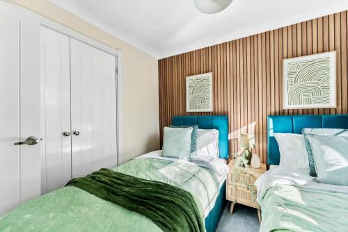 two beds in a bedroom with blue and white at Stylish 4 bed in Bracknell with Games Room in Bracknell