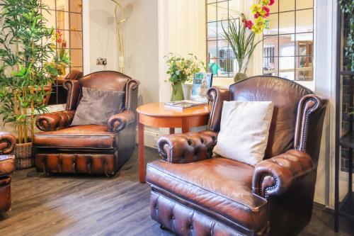 two leather chairs and a table in a room at OYO Tong Park Hotel in Bradford