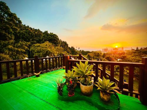 a green table with plants on a balcony with the sunset at Yue Ya Villa in Puli