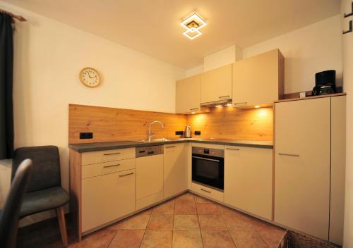 a kitchen with white cabinets and a clock on the wall at Apart am Brunnen in Ried im Oberinntal